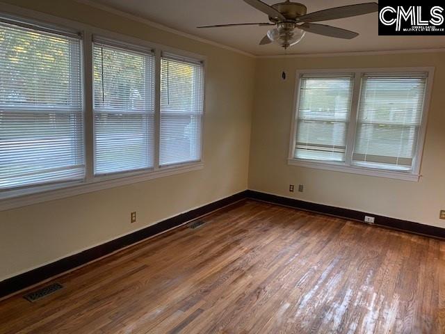 empty room featuring crown molding, ceiling fan, and wood-type flooring