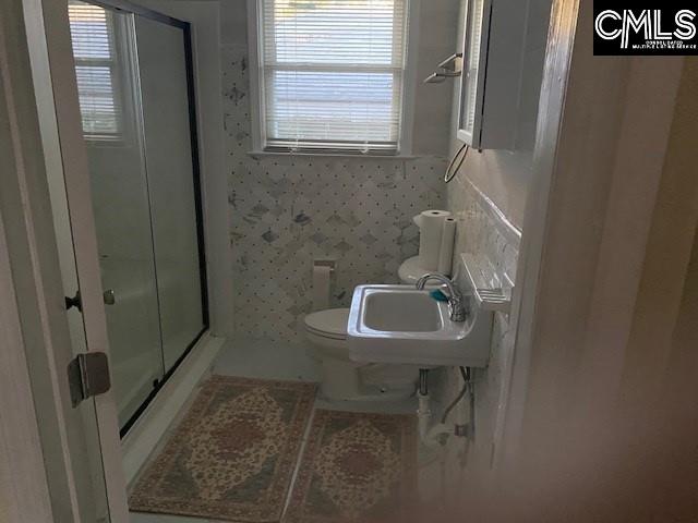 bathroom featuring an enclosed shower, sink, and toilet