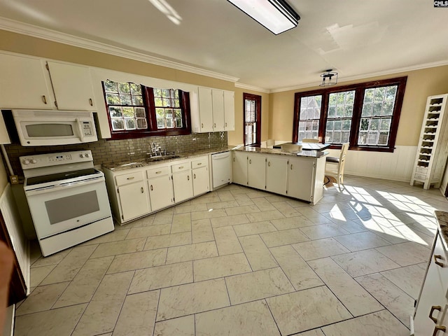 kitchen with white appliances, decorative backsplash, kitchen peninsula, ornamental molding, and white cabinetry