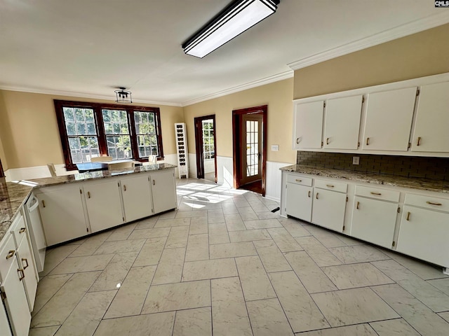 kitchen with kitchen peninsula, white cabinetry, light stone countertops, crown molding, and decorative backsplash