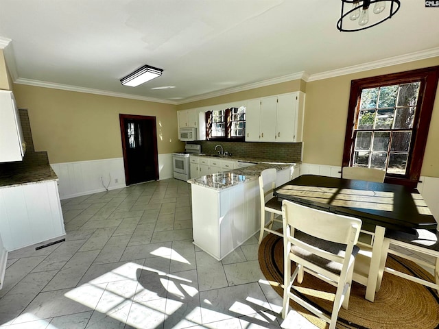 kitchen featuring white appliances, crown molding, white cabinets, and kitchen peninsula