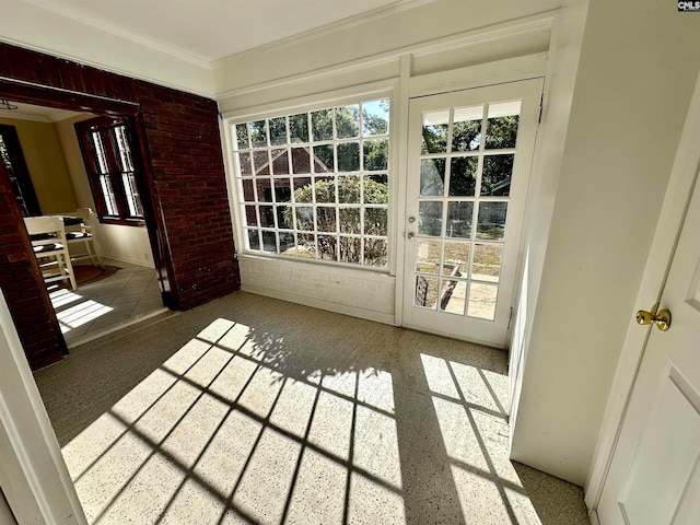 entryway featuring ornamental molding and brick wall