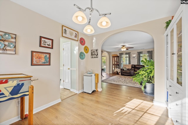 entrance foyer featuring ceiling fan with notable chandelier and light hardwood / wood-style floors