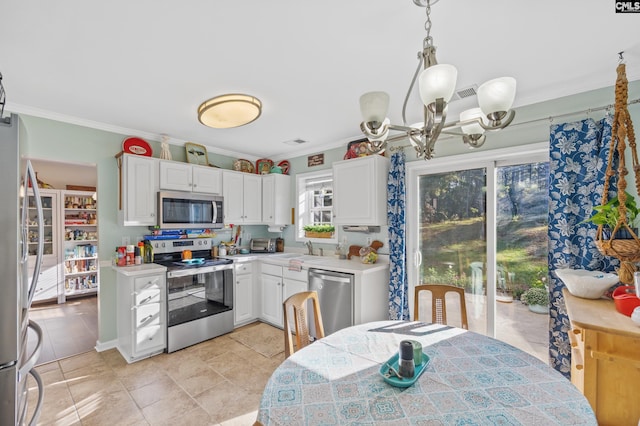 kitchen featuring pendant lighting, stainless steel appliances, crown molding, and white cabinetry