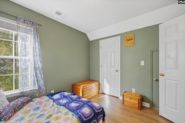 bedroom featuring lofted ceiling, hardwood / wood-style floors, and multiple windows