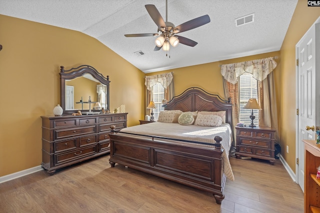 bedroom with a textured ceiling, vaulted ceiling, light wood-type flooring, and ceiling fan