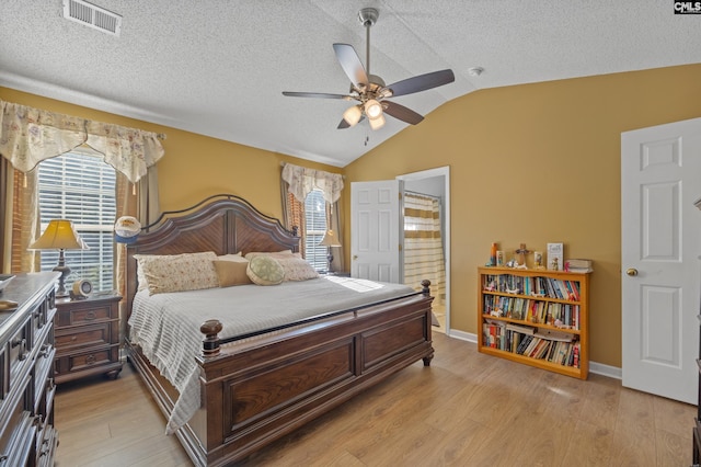 bedroom featuring lofted ceiling, ceiling fan, light hardwood / wood-style floors, and a textured ceiling