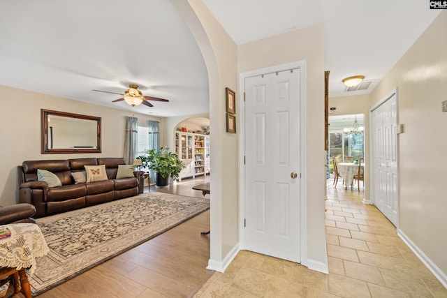 entryway with ceiling fan with notable chandelier, light hardwood / wood-style floors, and a healthy amount of sunlight