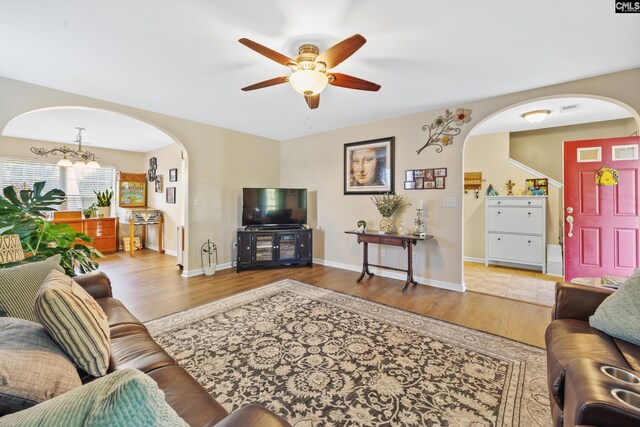 living room with wood-type flooring and ceiling fan with notable chandelier