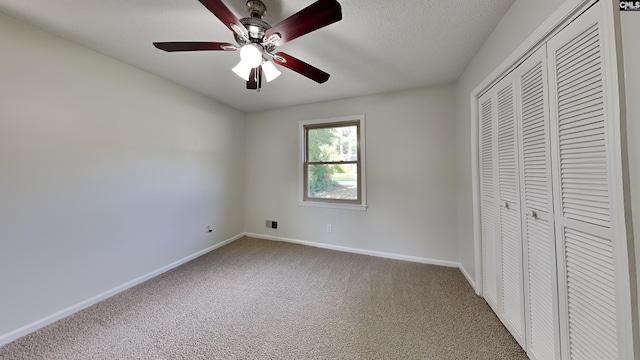 unfurnished bedroom with ceiling fan, carpet floors, a closet, and a textured ceiling