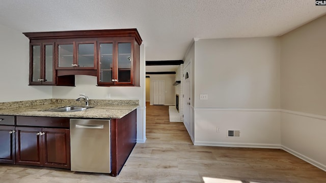 kitchen featuring light wood-type flooring, light stone countertops, sink, a fireplace, and dishwasher