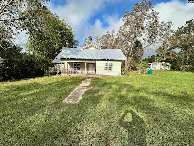 rear view of property featuring a lawn and a porch