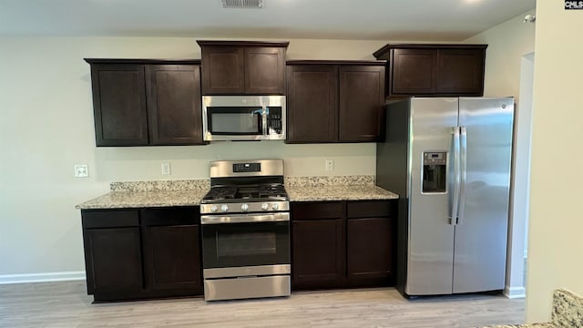 kitchen featuring light hardwood / wood-style flooring, light stone counters, stainless steel appliances, and dark brown cabinetry