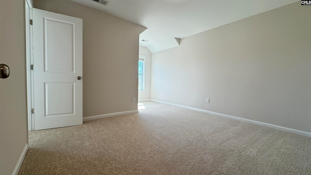 empty room with light colored carpet and vaulted ceiling