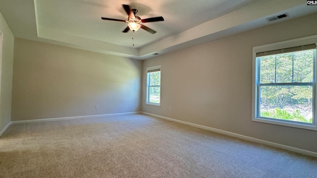 carpeted spare room featuring ceiling fan and a tray ceiling