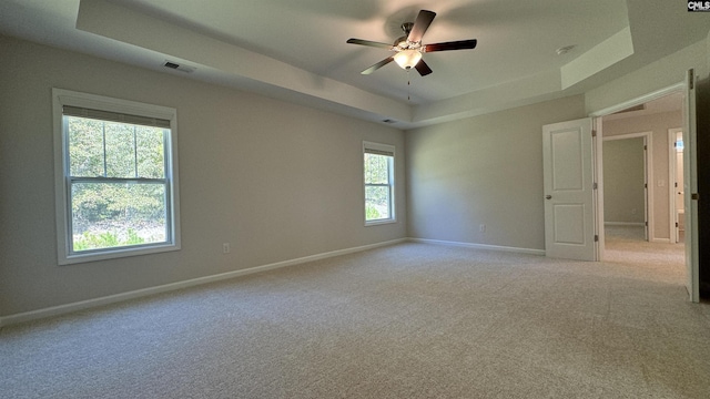 carpeted empty room with ceiling fan and a raised ceiling