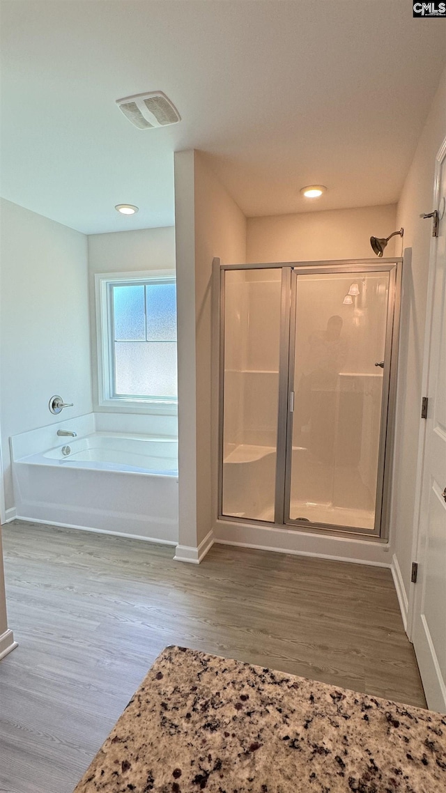 bathroom with independent shower and bath and hardwood / wood-style flooring