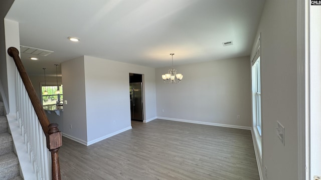 empty room featuring hardwood / wood-style floors and a notable chandelier