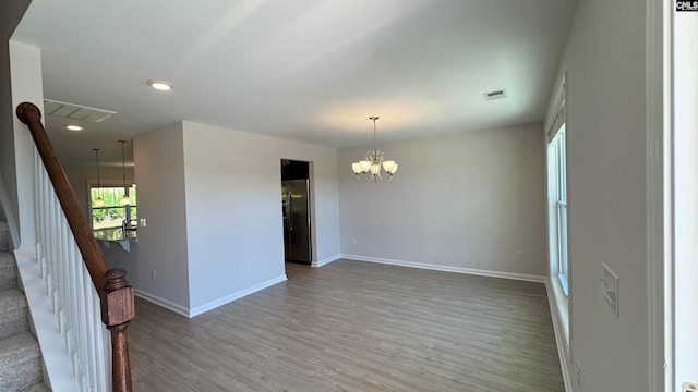 spare room featuring a chandelier and hardwood / wood-style flooring