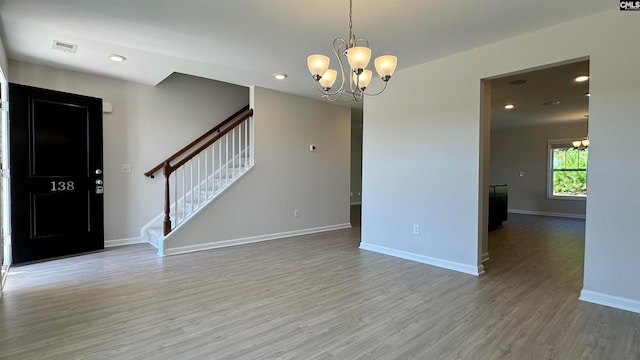 unfurnished room with an inviting chandelier and light hardwood / wood-style flooring