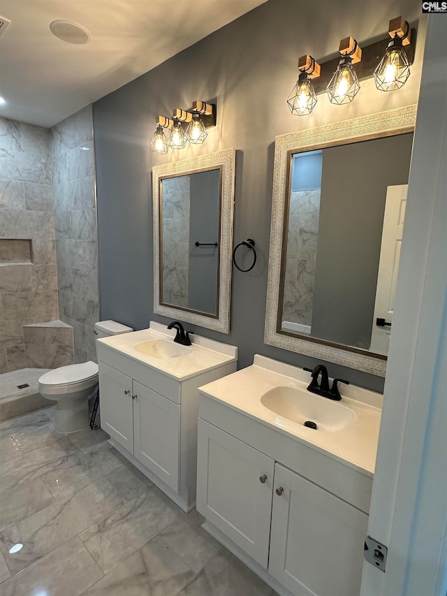 bathroom with vanity, toilet, and tiled shower