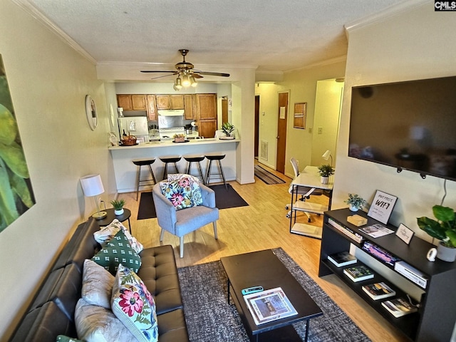 living room with a textured ceiling, crown molding, ceiling fan, and light hardwood / wood-style flooring