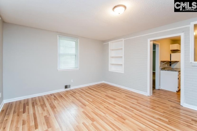 unfurnished room featuring light wood-type flooring and a textured ceiling