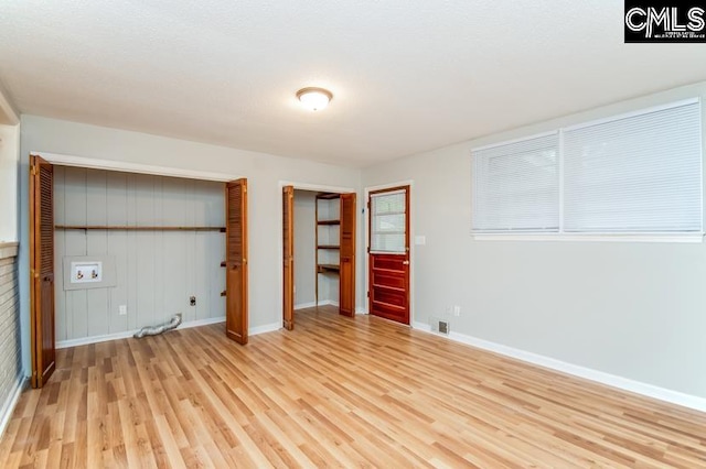 unfurnished bedroom with light hardwood / wood-style flooring and two closets