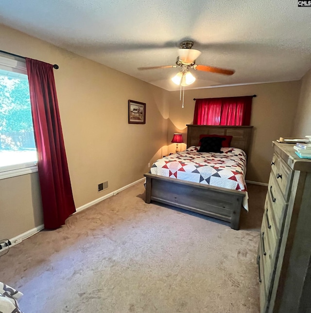 unfurnished bedroom with light colored carpet, a textured ceiling, and ceiling fan