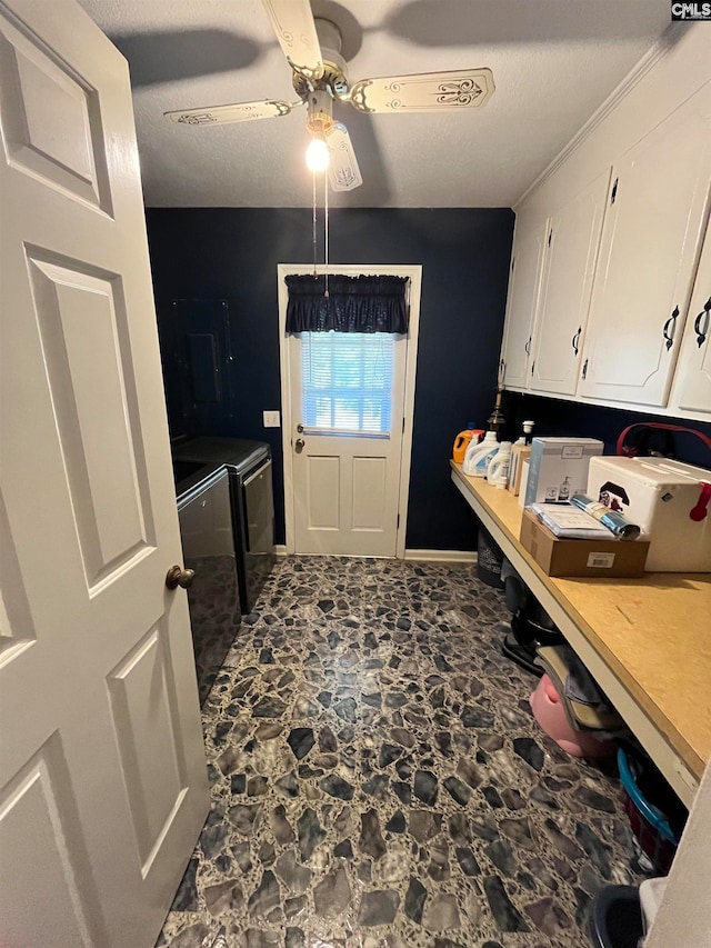 laundry room featuring ceiling fan, cabinets, washer and dryer, and a textured ceiling