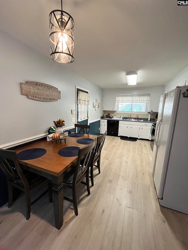 dining room with a notable chandelier, sink, and light hardwood / wood-style floors