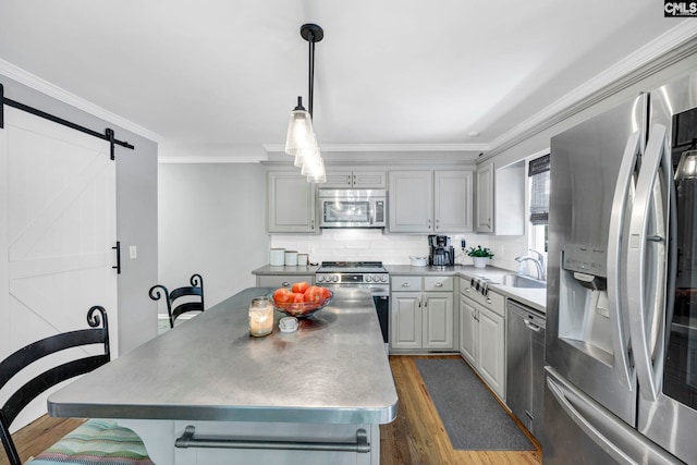 kitchen featuring dark hardwood / wood-style floors, gray cabinetry, ornamental molding, a barn door, and appliances with stainless steel finishes