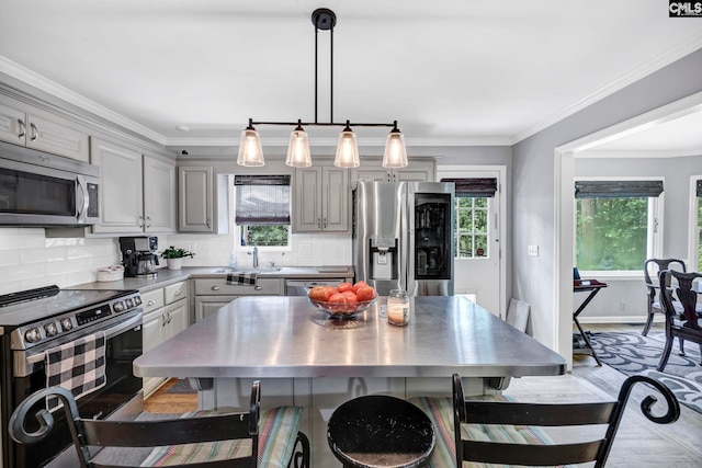 kitchen with gray cabinets, decorative backsplash, a center island, and stainless steel appliances