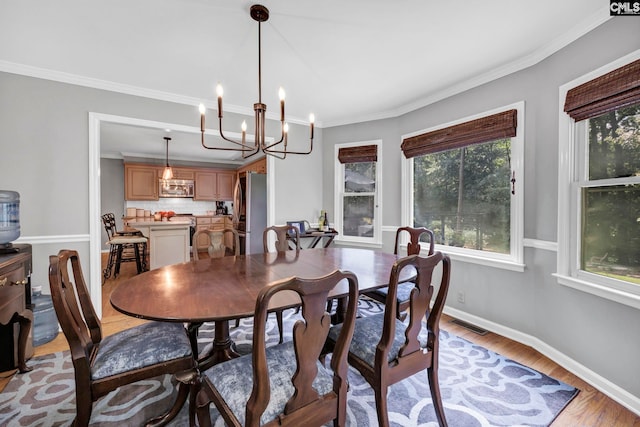 dining area featuring a chandelier, crown molding, and light hardwood / wood-style flooring