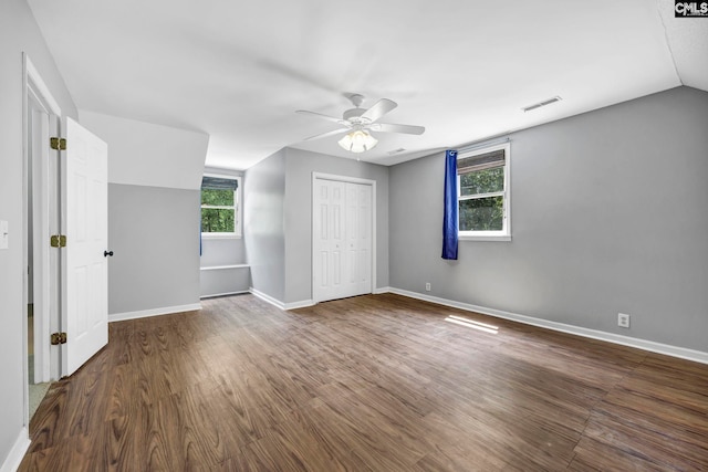 unfurnished bedroom with a closet, dark hardwood / wood-style flooring, multiple windows, and ceiling fan