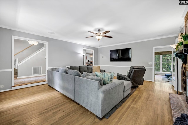 living room with ornamental molding, ceiling fan, and light hardwood / wood-style floors