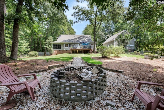 exterior space with a wooden deck, a patio, and an outdoor fire pit