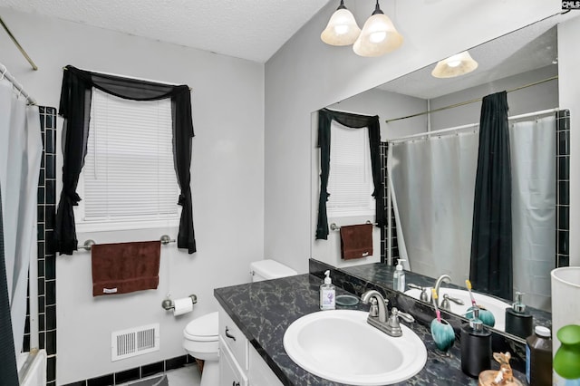 bathroom featuring walk in shower, toilet, tile patterned floors, vanity, and a textured ceiling