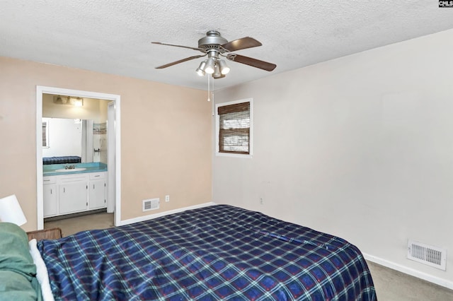 bedroom with ceiling fan, light colored carpet, sink, connected bathroom, and a textured ceiling