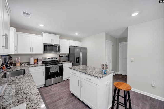 kitchen with a kitchen island, wood-type flooring, white cabinets, sink, and appliances with stainless steel finishes