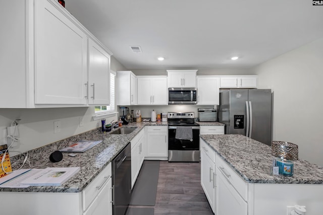 kitchen with dark hardwood / wood-style flooring, sink, stainless steel appliances, light stone countertops, and white cabinetry