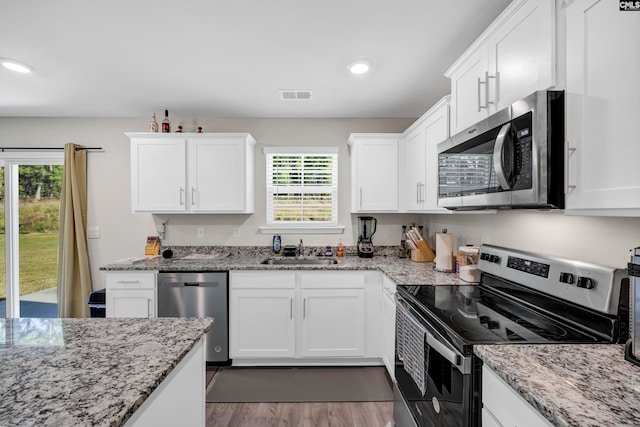 kitchen featuring white cabinets, appliances with stainless steel finishes, sink, and light stone countertops