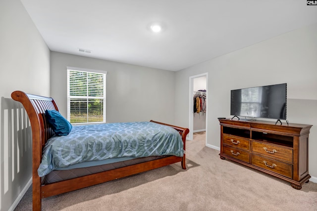 bedroom featuring light colored carpet, a closet, and a spacious closet