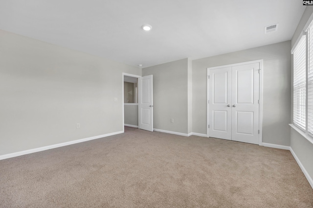 unfurnished bedroom featuring light colored carpet and a closet