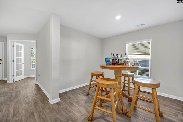 dining room with indoor bar, dark hardwood / wood-style flooring, and a healthy amount of sunlight