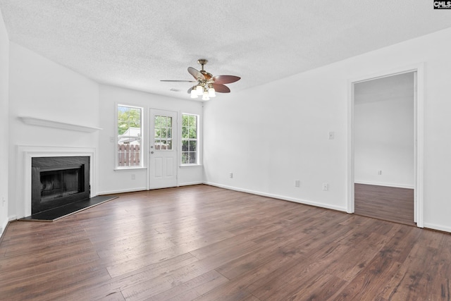 unfurnished living room featuring dark wood-type flooring, ceiling fan, a high end fireplace, and a textured ceiling