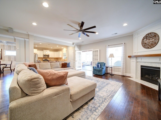 living room featuring dark wood-type flooring, ornamental molding, and ceiling fan