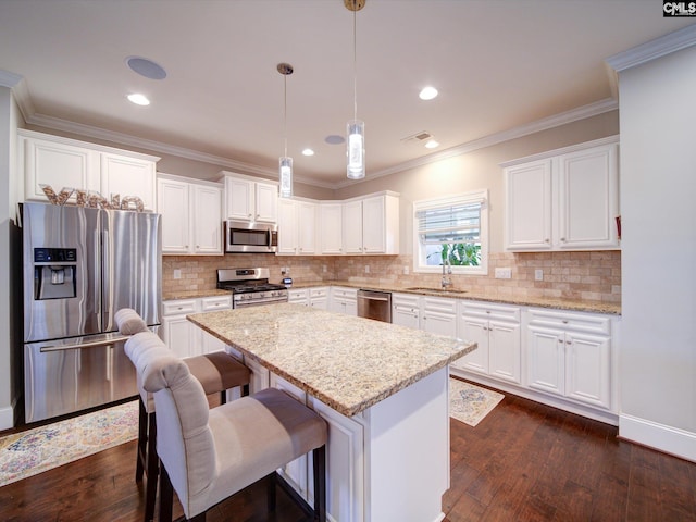 kitchen with appliances with stainless steel finishes, decorative light fixtures, white cabinetry, and dark hardwood / wood-style floors