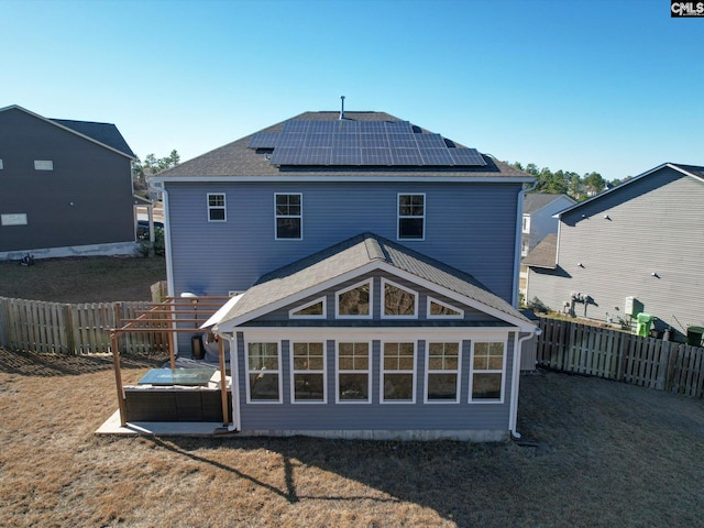 back of property featuring solar panels, a yard, and a sunroom