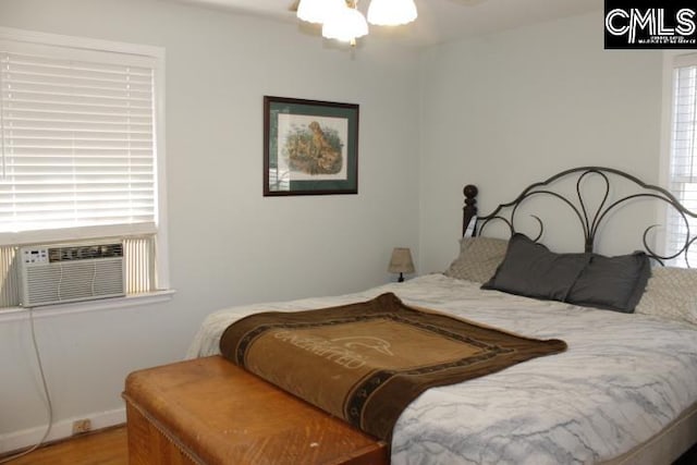 bedroom with multiple windows, hardwood / wood-style flooring, and cooling unit